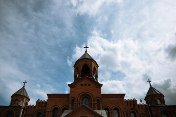 Armenian christian church against blue cloudy sky . Russia , Vladikavkaz