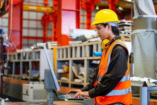 Engineering technician worker is operating the machine inside factory using touch screen computer monitor to command the order for line production and steel industry