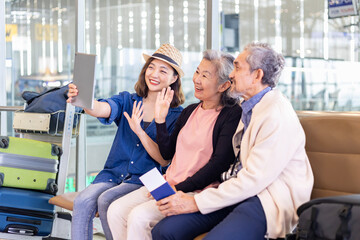 Group of Asian family tourist passengers with senior is using mobile phone to take selfie photo at airport terminal during vacation travel and long weekend holiday concept