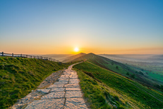 Stone footpath and wooden fence leading a long The Great Ridge in the English Peak District