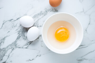 Fresh uncooked goose and chicken eggs on a white marble background, horizontal shot, above view