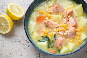 Middle closeup of chowder with salmon fillet, horizontal shot on a beige granite surface, selective focus