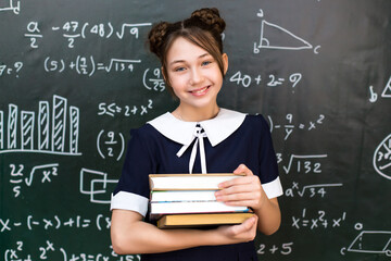 Girl schoolgirl with four books in her hands, concept of school life preparing for exams.