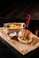 burger with french fries and sauce on a wooden table in a bar
