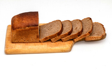Slices of dark wholemeal bread next to a loaf on wooden chopping board
