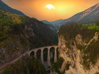 Aerial view of Train passing through famous mountain in Filisur, Switzerland. Landwasser Viaduct world heritage with train express in Swiss Alps
