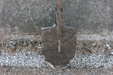 Fototapeta premium A dirty shovel against the background of a wall with stones. Gardening photography.