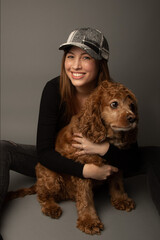 Studio portrait of a caucasian woman in her 30s with her cocker spaniel adult dog. The woman is...