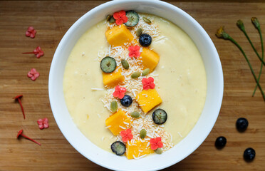 Pina colada inspired smoothie bowl made from pineapple, passion fruit, banana, lime and oat coconut milk and yogurt topped with kiwi fruit and goji berry and fresh shredded lime skin