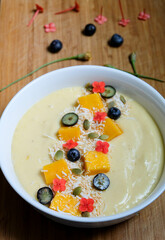 Pina colada inspired smoothie bowl made from pineapple, passion fruit, banana, lime and oat coconut milk and yogurt topped with kiwi fruit and goji berry and fresh shredded lime skin