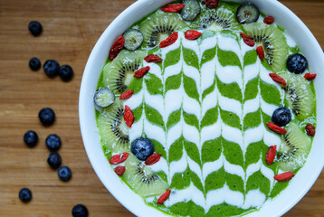 Green smoothie bowl made from kale, spinach, banana, pineapple and lime topped with fresh kiwi...