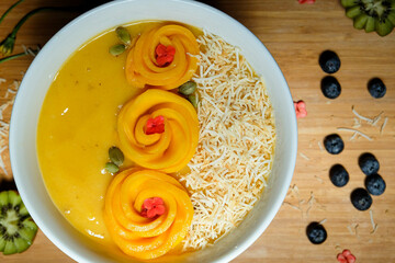 Mango, Pineapple, Passion fruit, Banana and oat coconut milk smoothie bowl topped with fresh mango,...