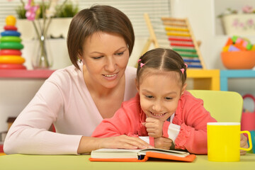 Fototapeta premium pretty young mother reading a book to her daughter