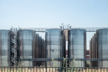Stainless steel storage tanks or vats for wine fermentation and maturation in modern winery factory production. Industrial and technology background
