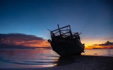 Foto op Canvas Wreck of a fishing boat on the beach © saksuvan
