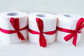 Three toilet paper rolls wrapped in gift bow. Covid19 concept