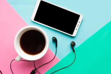 Flat lay photo with coffee cup and mobile phone on pink, blue and green geometric  background.
