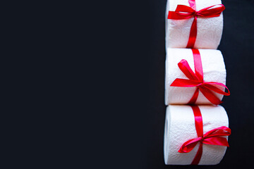 toilet paper rolls wrapped in gift bow on bright black background. Covid19 concept