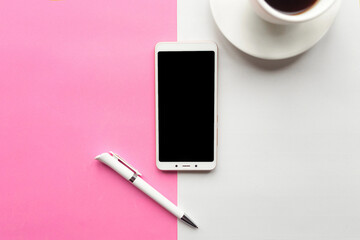 Flat lay photo with coffee cup and mobile phone on pink background.
