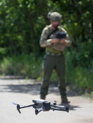 Dron z obsługującym go żołnierzem w tle - obrazy, fototapety, plakaty