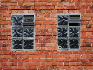 Two old windows, red brick wall on an old farmhouse
