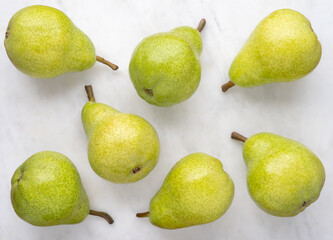 Green pears on white marble background, top view