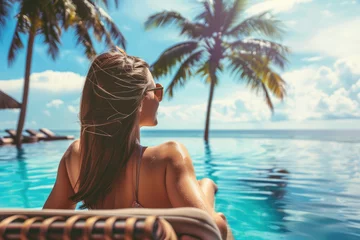 Foto op Aluminium Woman sunbathing in bikini at tropical travel resort. Beautiful young woman lying on sun lounger near pool © Kien