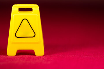 Yellow plastic warning sign on a red floor. Yellow warning sign with empty space for your text