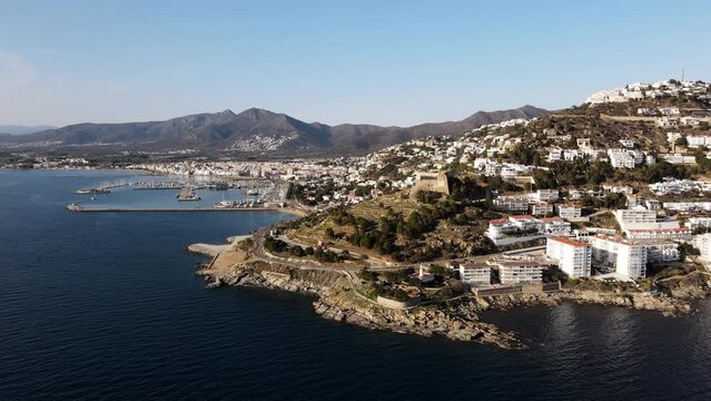 Drone shot of the Castle of La Trinitat overlooking the coastal town of Roses in Spain. Costa Brava during sunset.