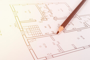 A graphite pencil lies on a piece of paper where there is a house project. close-up. there is a tinting