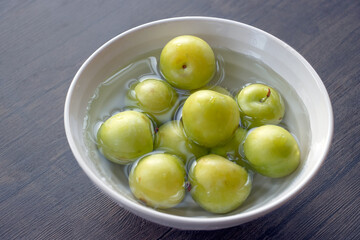 closeup of green plums on a white bowl