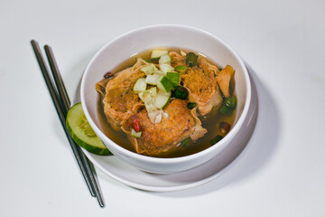 Asian food called gohyong, with fresh vinegar sauce filled with fried minced chicken, served in a bowl and decorated with iron chopsticks and a slice of cucumber