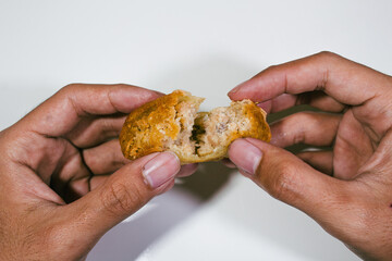 one fried dish containing chopped chicken is served held in two hands and cut in half
