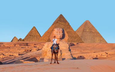 Camels in Giza Pyramid Complex - A woman riding a camel across the thin sand dunes - Cairo, Egypt