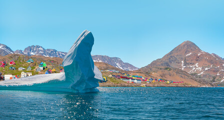 Melting of a iceberg and pouring water into the sea by the coast of Greenland - Picturesque village...