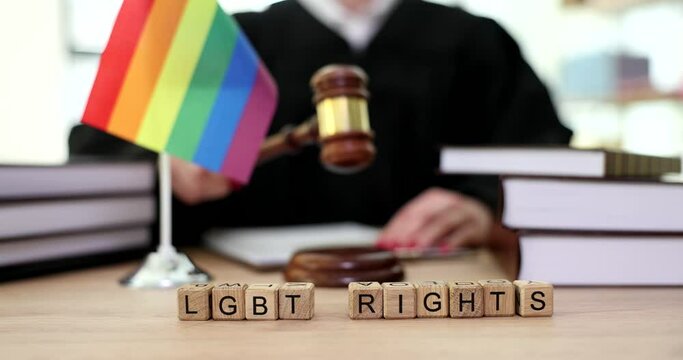 Lgbt rights word near rainbow flag and judge in courtroom closeup 4k movie slow motion. Legalization of samesex marriage concept