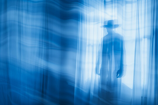 The hat man ominous silhouette of a man wearing a top hat in the room. Paranormal sleep paralysis shadow man ghost figure.