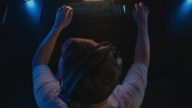 Gamer in headset plays on gaming keyboard with RGB lighting and mouse. Esports tournament at computer club Cyber team Video games. Personal skill. Tactical first-person shooter. Cyrillic letters WASD
