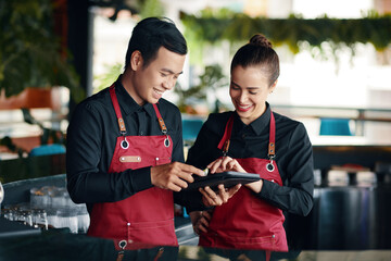 Restaurant manager teaching waiter how to use application when checking orders