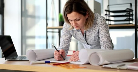 A young woman in the office makes a drawing on whatman, a close-up. The workplace of the architect
