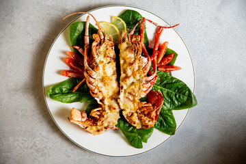 Grilled lobster with lemon and green leaves on a white plate. Delicious lobster Thermidor served on porcelain plate