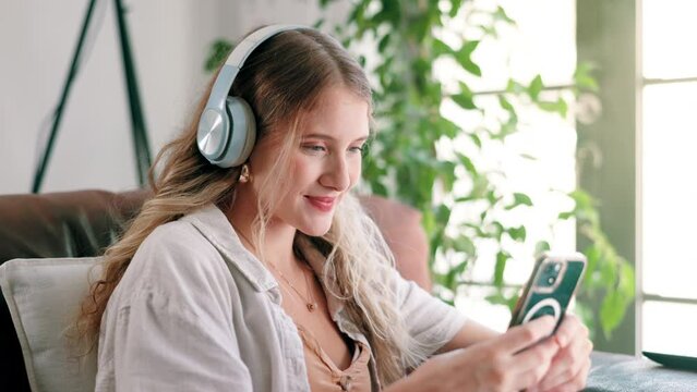 Phone, headphones and woman on sofa at house networking on social media, mobile app or internet. Smile, typing and female person listening to music, radio or album on cellphone in living room at home