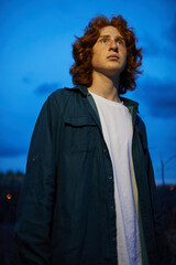 Red-haired young man gazing up into the twilight sky