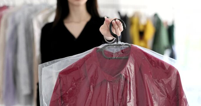 The woman in dry cleaning holds out a hanger with clothes, a close-up. Ironing and caring for clothing