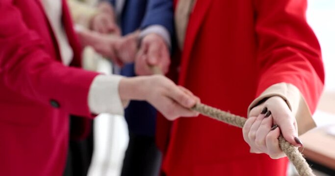 A team of young employees pulls a rope, a close-up. Team building in the office, business people, slowmotion