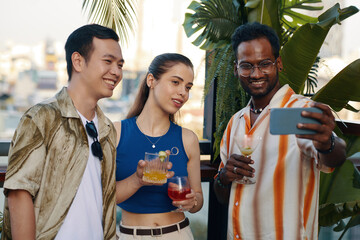 Smiling man taking selfie with best friends at party