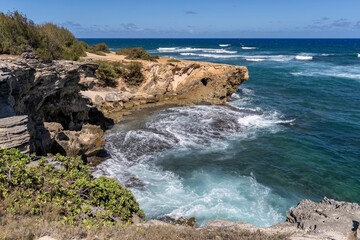 The turquoise waters of the Pacific Ocean slam against jagged rocks along the Mahaulepu Heritage...