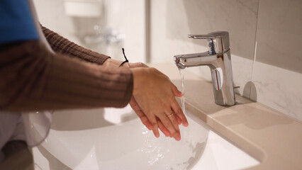 Young woman washing hands in the bathroom