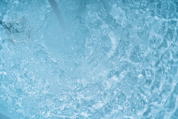 Stream of water flows from a faucet into a swimming pool.