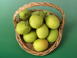 A basket of fresh fruit pears on a green background